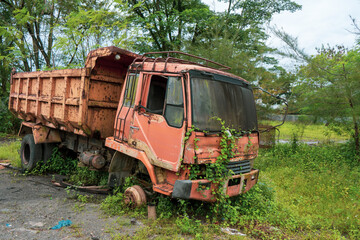 Side view of a broken old truck that has been badly damaged abandoned in the middle of a park