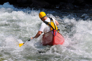 canoeist in red canoe in rapids of a river