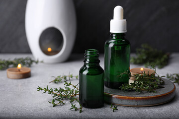 Thyme essential oil on light grey table, space for text