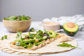 Tortilla with hummus and vegetables on table, closeup