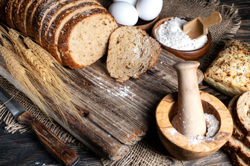 Fototapeta na wymiar loaf of rye bread, ears of wheat, eggs and a bowl of flour. Close-up.
