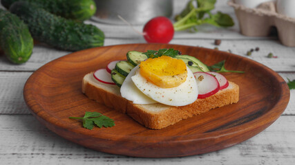 Tasty sandwich with boiled egg, radish and cucumber on white wooden table, closeup
