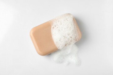 Soap with fluffy foam on white background, top view