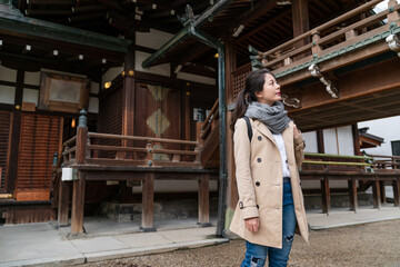 Fototapeta premium cheerful Asian Japanese girl visitor admiring beauty of ancient religious Shinto buildings while looking around at Osaka Tenmangu Shrine in japan