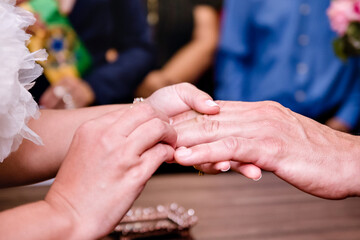 Fototapeta premium the hands of the bride and groom exchanging rings and in the background people watching