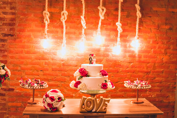 a biscuit wedding couple on top of a wedding cake decorated with red roses
