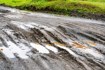 Waterlogged sandy path at a park with the multiple vehicle's tracks