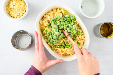 Dinner meal preparation, woman’s hand mixing together ingredients for tuna noodle casserole 
