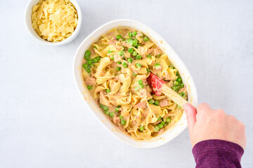 Dinner meal preparation, woman’s hand mixing together ingredients for tuna noodle casserole 
