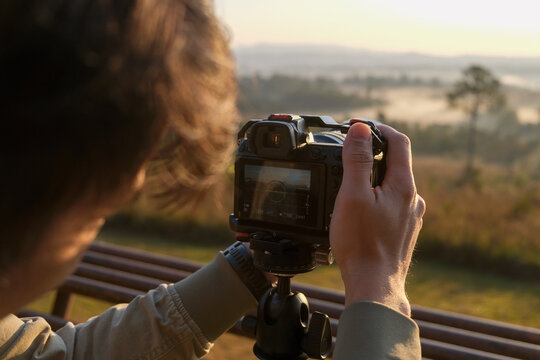 The photographer uses a camera to take pictures. At sunrise in the valley with rich nature travel and technology concept