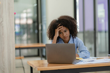 Frustrated business woman with stress headache thinking about a project or deal Massage her head with her hands. She has a headache. She sits at the table. Needs rest.