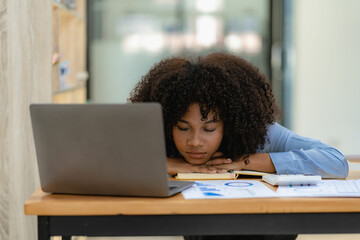 Tired and overworked business woman Tired young girl lying on the desk during her work using laptop and financial graph papers.