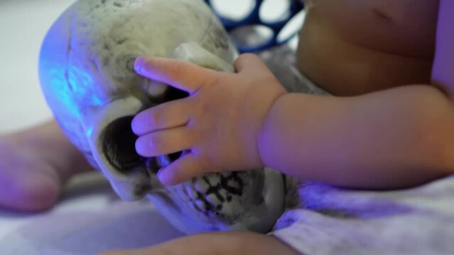 Close up the hand of baby boy hold skull. Horror theme concept