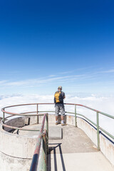 tourist with yellow backpack at a viewpoint with a view of a volcano crater in Irazu Volcano National Park in Costa Rica on a sunny day
