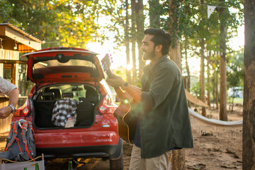 Men tourists drinking beer-alcohol and play guitar together with enjoy and happiness in Summer while camping