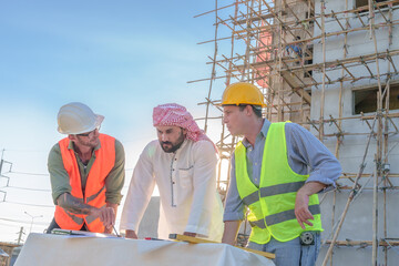 Diverse team of professionals using tablet computers on construction site. Real estate construction...