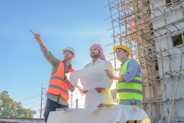 Diverse team of professionals using tablet computers on construction site. Real estate construction project. with civil engineers, architects, Arabic business investors and explorer with theodolite