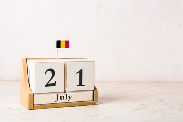 Cube calendar and small Belgian flag on table near light wall