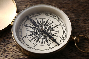 Fototapeta na wymiar Golden compass on dark wooden background, closeup