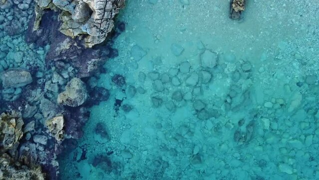 Crystal clear turquoise water in secluded Sardinian bay, aerial top down, orbit