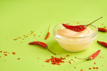 Bowl of tasty chipotle sauce and dry peppers on green background