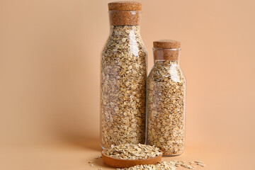 Bottles of raw oatmeal on color background