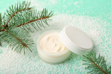 Fototapeta na wymiar Jar of cream, fir branches and snow on color background