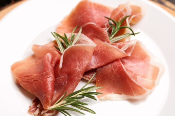 Plate with slices of tasty ham and rosemary, closeup
