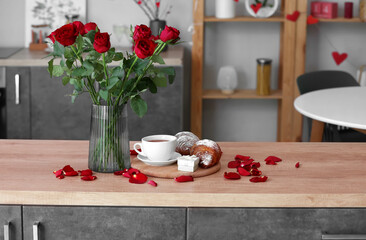 Engagement ring, cup of tea, croissants and vase with roses on counter in kitchen decorated for Valentine's Day