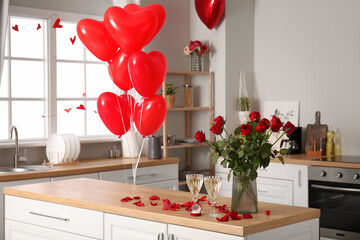 Engagement ring, vase with roses and glasses of champagne on counter in kitchen decorated for Valentine's Day