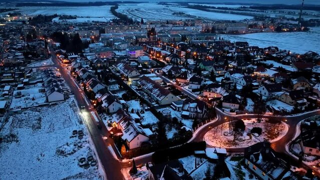 City of dawn in winter. Snow covered streets with street lighting. Family houses in a developing neighborhood. Starting Christmas holidays with lights and decorations. Aerial view