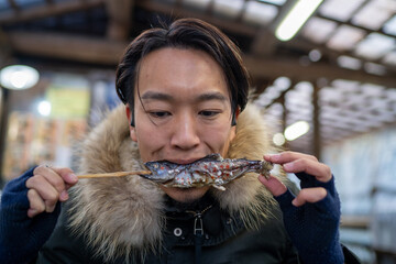 焼きイワナにかぶりつく男性