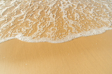 Fototapeta na wymiar Close-up of a beach with a calm transparent wave. Romantic sea coast with golden sand.