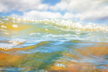 A close-up of the sea water surface in soft focus. The sea in the light of the sun's rays in the hot summer. Background on the theme of serenity, travel and beach vacation.