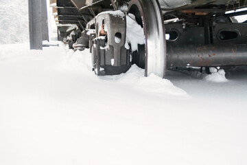 Close-up of the wheels of a freight train car stuck in deep snow.