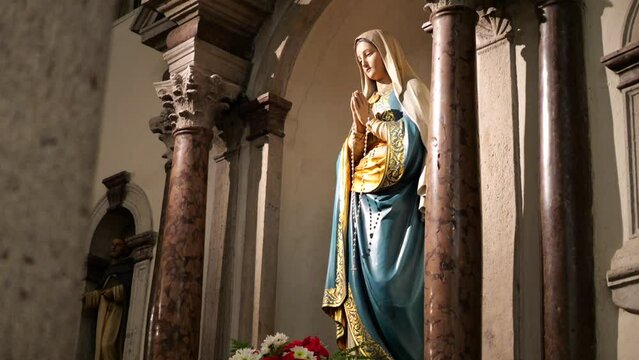 Tilt Up Shot Of Our Lady Virgin Mary Statue Inside Church With Colorful Flowers Bouquet 