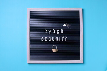 The word cyber security, padlock and key on letterboard isolated on blue background. 