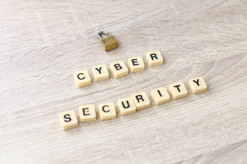 Lock and alphabet square tiles with the word cyber security on wooden background. Cyber security concept.