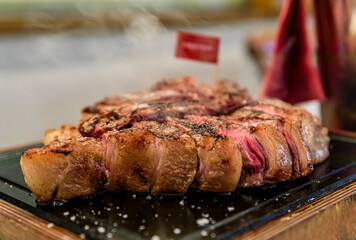 Classic seared dry aged T-bone Florentine steak from a Chianina cow steaming on a grill serving plate at a restaurant in Florence, Italy