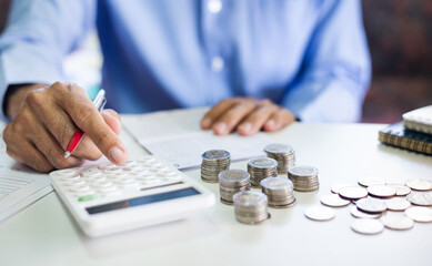 Asian businessman on desk in office using calculator to calculate saving account passbook and...