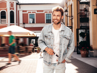 Portrait of handsome smiling stylish hipster model. Sexy man dressed in jeans jacket. Fashion male...
