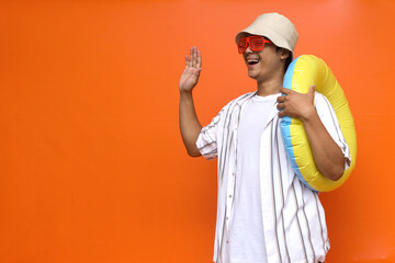 Young traveler holding yellow rubber ring while waving hello hi or goodbye gesture © Gatot