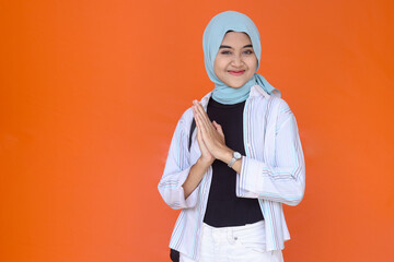 Portrait of a young muslim woman in casual wear with backpack isolated over orange background