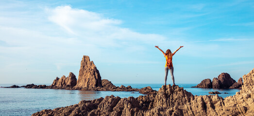 happy woman looking at rock formation in sea- Cabo de gata,  Spain - obrazy, fototapety, plakaty