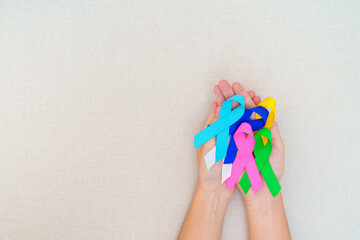 World cancer day, February 4. Hand holding blue, red, green, white, pink, navy blue and yellow...