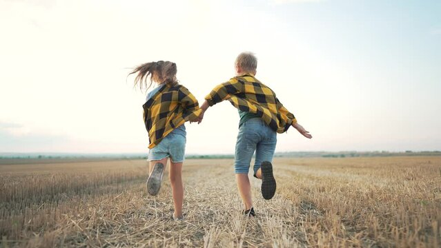 Happy family. boy and girl run holding hands in a wheat field. Active children in autumn in the field. Family in nature. Freedom of the countryside. Children run outdoors in park. Natural park summer