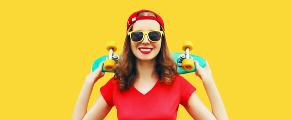Summer portrait of happy smiling young woman with skateboard wearing red baseball cap isolated on yellow background