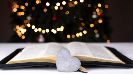 An open Bible on the table. The heart is a symbol of God's love for people. Prayer. On the...