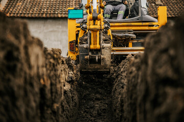 Cropped picture of a backhoe digging soil on construction site and making foundation.