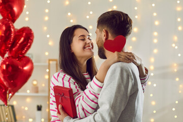 Couple in love tenderly hug each other while giving each other gifts on Valentine's Day. Happy...